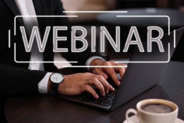 Çevrimiçi webinar. Ahşap masada dizüstü bilgisayar kullanan adam, yakın plan.
