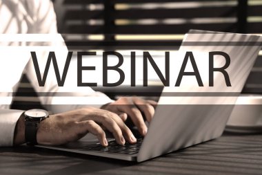 Çevrimiçi webinar. Ahşap masada dizüstü bilgisayar kullanan adam, yakın plan.