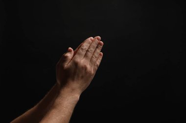 Din. Hıristiyan adam siyah arka planda dua ediyor, yakın plan. Metin için boşluk