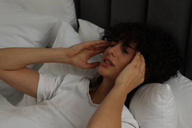 Geceleri yatakta baş ağrısı çeken genç bir kadın.