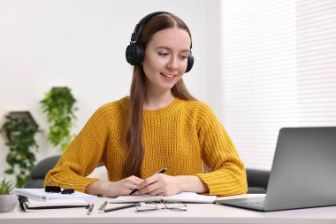 E-öğrenme. Beyaz masa içerisindeki online derste not alan genç bir kadın.