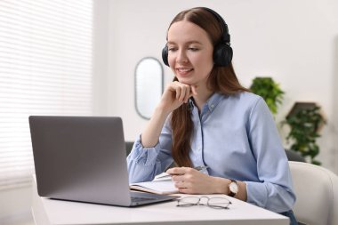E-öğrenme. Beyaz masa içinde online ders sırasında dizüstü bilgisayar kullanan genç bir kadın.