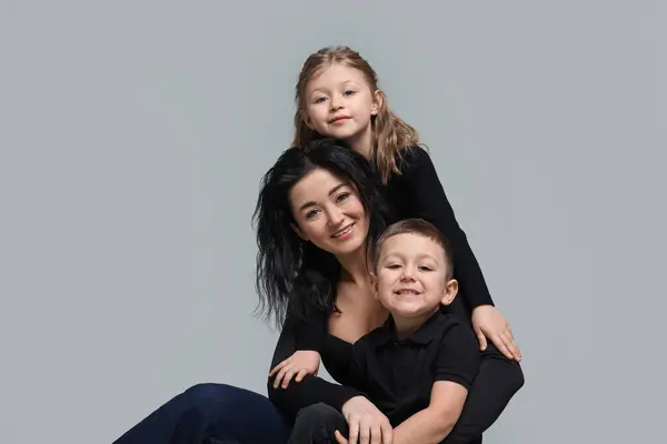 stock image Little children with their mother on grey background
