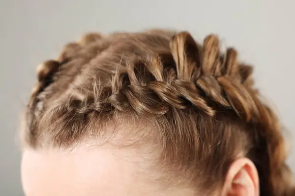 Woman with braided hair on grey background, closeup