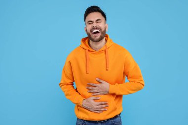 Yakışıklı genç adam açık mavi arka planda gülüyor.