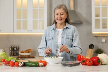 Mutfaktaki masada salata yapan mutlu kadın.