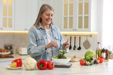 Mutfaktaki masada salata yapan mutlu kadın.