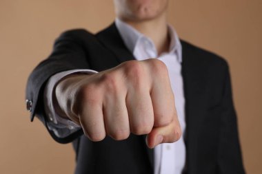 İş adamı, bej arka planda dövmesi için yeri olan yumruğunu gösteriyor, seçici odaklı