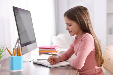 E-öğrenme. İçerideki masada online ders sırasında not alan tatlı kız.