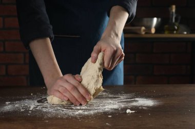 Ekmek yapıyorum. Mutfaktaki ahşap masada hamur yoğuran kadın, yakın plan.