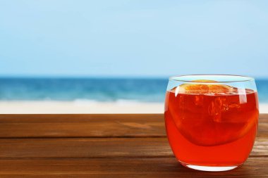 Plajdaki ahşap masada portakal dilimli Aperol sprey kokteyli. Metin için boşluk