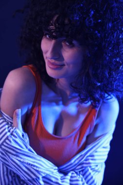 Neon ışıklarıyla arka planda poz veren güzel genç kadın, yakın plan.