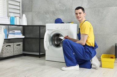 Gülümseyen tesisatçı banyodaki çamaşır makinesinin sonuçlarını yazıyor.