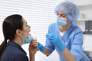 Laboratuvar testi. Doktor hastanede pamuklu çubukla hastanın ağzından örnek alıyor.