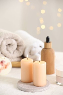 Spa kompozisyonu. Yumuşak beyaz yüzeyde mum ve kişisel bakım ürünleri yakmak