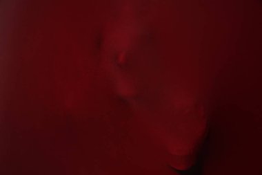 Kırmızı kumaşın arkasında kafatasları olan ürkütücü bir hayalet silueti.