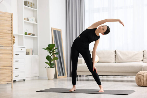 Girl stretching on yoga mat at home. Janu Sirsasana pose variation