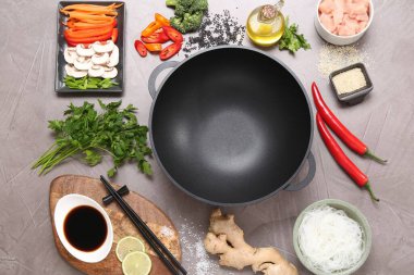 Wok, yemek çubukları ve gri desenli masa üzerinde farklı ürünler, düz yatak