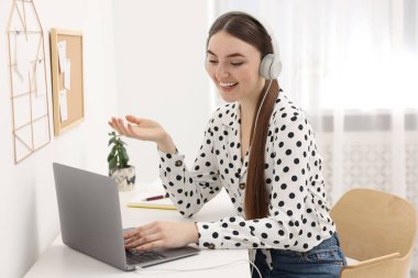 E-öğrenme. İçerideki masada online ders sırasında dizüstü bilgisayar kullanan genç bir kadın.