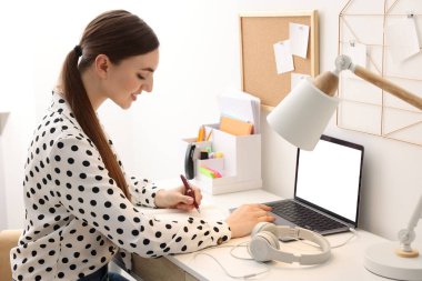 E-öğrenme. İçerideki masada ders alan bir kadın.