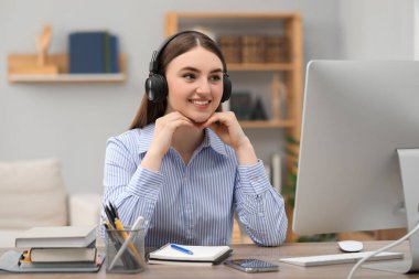 E-öğrenme. İçerideki masada online ders sırasında bilgisayar kullanan genç bir kadın.