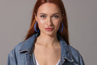 Gri arka planda kot ceketli güzel bir kadın.