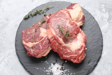 Açık gri desenli masa üzerinde farklı baharatlarla kesilmiş taze çiğ et.