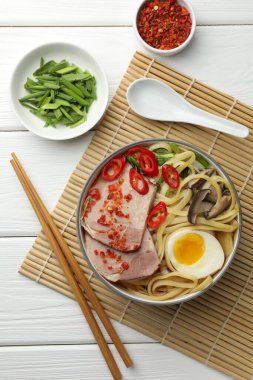 Tabaktaki lezzetli ramen beyaz ahşap masada servis ediliyor. Erişte çorbası.