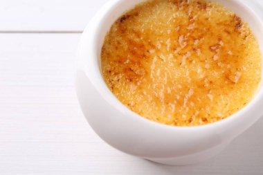 Lezzetli creme brulee kasede beyaz ahşap masada, yakın plan