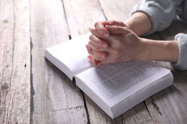 Din. Hıristiyan kadın ahşap masada İncil için dua ediyor, yakın plan.