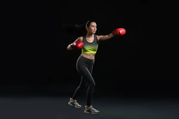 stock image Beautiful woman in boxing gloves training on black background