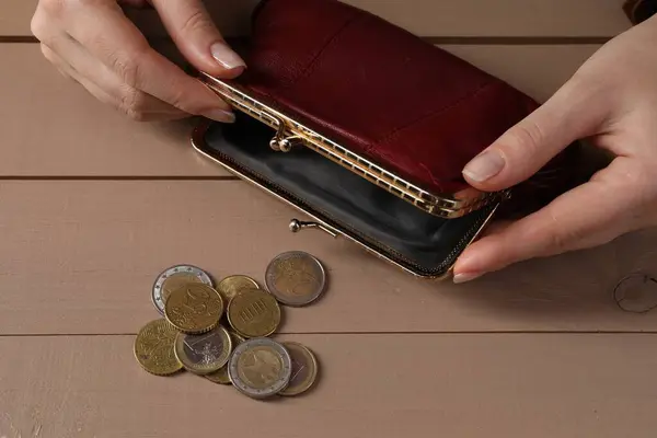 Poverty. Woman with empty wallet and coins at wooden table, above view