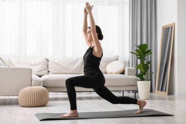 Evde yoga minderinde hilal asana pratiği yapan bir kız. Yüksek atlama pozisyonu