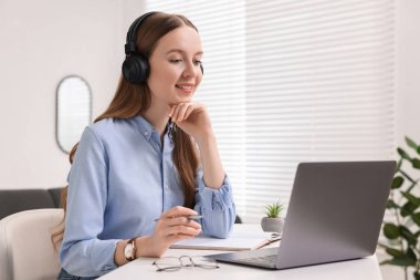 E-öğrenme. Beyaz masa içinde online ders sırasında dizüstü bilgisayar kullanan genç bir kadın.