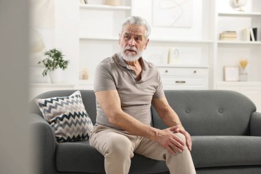 Artrit belirtileri. Evinde diz ağrısı çeken bir adam.