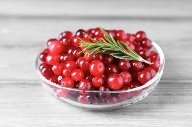 Taze kızılcıklar ve biberiye kasede Gri ahşap masada, yakın plan