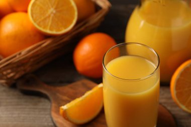 Lezzetli taze portakallar ve meyve suyu ahşap masada, yakın plan.