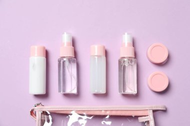 Kozmetik seyahat seti. Küçük kaplar dolusu kişisel bakım ürünleri ve mor arka planda plastik torbalar, düz konteynırlar.