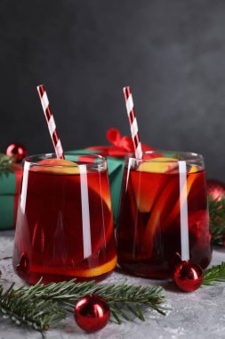 Gözlüklü lezzetli Sangria içkisi ve gri desenli masa üzerindeki Noel süslemeleri, yakın plan.