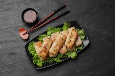 Lezzetli kızarmış börek, marul ve sos siyah masada, üst tarafta.