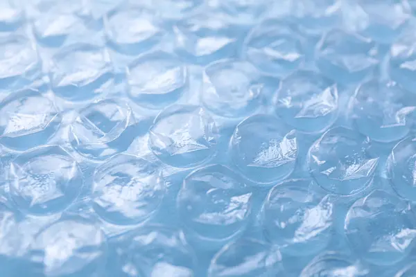Transparent bubble wrap on light blue background, closeup