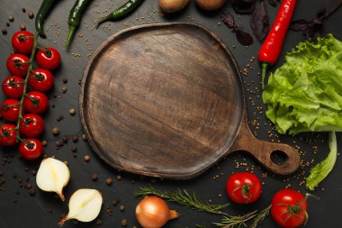 Yemek pişirme konsepti. Tahta kesme tahtası ve siyah masa üzerinde farklı ürünler, düz yatıyordu.