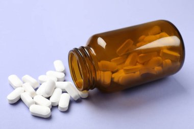 Mor arka planda şişe ve vitamin kapsülleri
