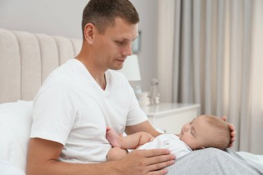 Mutlu baba tatlı uyuyan bebeğini evde tutuyor.