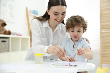 Anne ve küçük oğlu evde suluboya resim yapıyorlar.