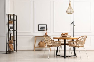 Ahşap masa ve hasır sandalyelerle dolu bir yemek odası.