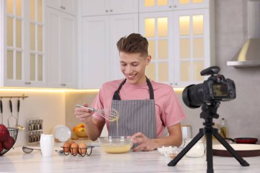 Mutfakta video kaydederken gülümseyen yemek blogcusu yemek pişiriyor