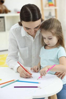 Anne ve küçük kızı evde renkli kalemlerle resim yapıyorlar.