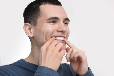 Dişlerini beyazlatan bir şerit takan genç bir adam.