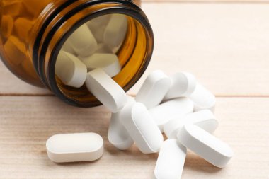 Şişe ve vitamin hapları ahşap masada, yakın plan.